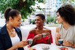 Three mixed race hispanic and black women bonding outdoors at the bar cafe