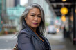 © KirKam - Elegant Mature Asian Woman Posing Confidently on a Busy City Street Corner.