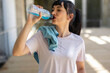 Young adult woman refreshes herself with an energy drink after exercise outdoors