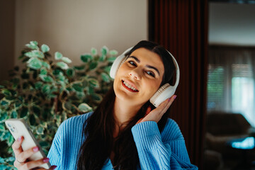 One young girl or woman is listening to music on her wireless headphones in the morning before going to work	