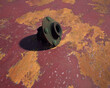 Old rusty metal wheel hub on rusty metal sheet with weathered red paint.