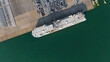 Aerial drone photo of large car carrier ro ro vessel guided by tug boats to dock to Mediterranean port.