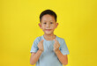 Asian boy child show finger mini heart symbol sign language isolated on yellow studio background.