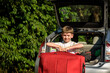 Pretty boy loading the luggage in the trunk of the car. Kid looking forward for a road trip or travel. Family travel by car