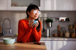 Woman drinking coffee at kitchen counter
