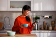Woman using smart phone and drinking coffee at home