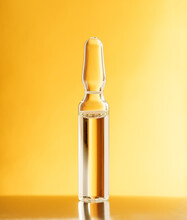 Glass Ampoule On A Gold Orange Background. Blister With Liquid. Pharmaceutical Equipment Concept