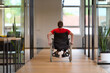 © .shock - A modern young businesswoman in a wheelchair is surrounded by an inclusive workspace with glass-walled offices, embodying determination and innovation in the business world