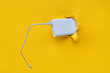 A white metal power bank protrudes from a torn hole in yellow paper. Concept of smartphone charging and mobile energy independence.