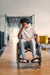© .shock - A African-American teenager in a wheelchair sits sadly amidst the bustling backdrop of a modern startup office, surrounded by his business colleagues.