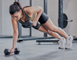 Woman, push up and dumbbell in gym for power, exercise and training for strong arm muscle. Female person, bodybuilder and athlete for sport and health, core and equipment for workout or weightlifting