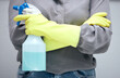 Person, spray and bottle in studio for cleaning dust, disinfecting and sanitation for health and hygiene. Woman or housekeeper, liquid detergent and isolated on grey background with arms crossed