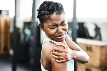 Black woman, shoulder and injury from training at gym with accident or muscle pain for fitness. Fit, female person and massage arm for medical healthcare after sprain or sore from physical activity