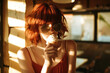 Girl with red hair in glasses holding ice cream in a waffle cone in cafe, hard light.