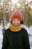 Fototapeta  - Cute cheerful African American boy in winterwear looking at camera with toothy smile while standing in natural environment on winter day