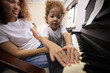 Funny Girl amd Happy Mother Play on Piano Together. Hobbies For Mother and Young Daughter. Happy Mother with Little Girl Play on Piano. Positive Day for Beautiful Woman. Young Daughter.
