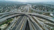 Aerial shot of a sprawling highway interchange with cars weaving through multiple lanes, illustrating complex urban infrastructure.