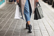 Woman, shoes and walking with shopping bags in street for fashion, purchase or heels in city. Legs of female person, shopper or customer in stroll on sidewalk with gifts for buying in an urban town