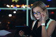 Close up of young businesswoman working on digital tablet in office. Beautiful female working late night in office sitting on a table with smartwatch on her hand