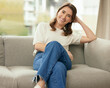 Portrait, smile and woman on couch in home living room for relax, calm and peace in apartment in Germany. Jeans, confidence and happy girl on sofa for comfort in lounge in casual clothes in house