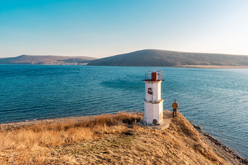 Poster - View of the lighthouse on the shore of the Sea of Japan and the island on the horizon. Lighthouse on the edge of the Eurasian continent on a sunny day. Russky Island, Vladivostok, Russia.