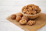 Fototapeta Na sufit - Walnuts in Wooden Bowl or Wicker Basket. Whole Walnut on White Table with Burlap