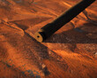 Old rusty axle shaft on weathered rusty metal sheet.