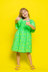 Wall Mural - Like. Happy preteen child girl kid looking approvingly at camera showing thumbs up, like sign positive something good, positive feedback great news. Children isolated on yellow background. Vertical