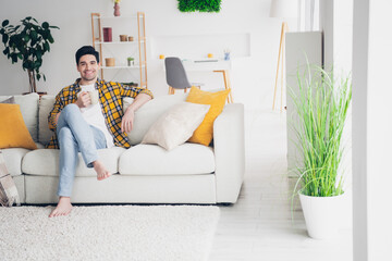 Canvas Print - Photo of handsome cheerful guy dressed plaid shirt enjoying weekend drinking tea relaxing sofa indoors room home house