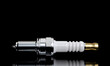 High-quality image of a spark plug isolated on a reflective black surface