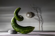 Modern still life with a crooked cucumber and stone