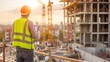 © Svfotoroom - Construction worker with helmet and reflective vest holding clipboard at construction site during sunset.