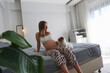 Happy pregnant woman bonding with her funny furry jack russell terrier pup on the bed at home. Copy space, background.