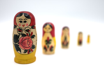 Detail of the typical Russian dolls that are placed inside each other. Originally called Matrioshka or hand-painted wooden Matrioska on a white background. They are lined up with a lot of bokeh