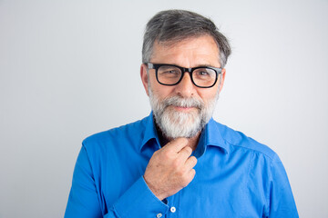 Poster - Portrait of happy mature man wearing spectacles and looking at camera indoor. Man with beard and glasses feeling confident. Close up face of Hispanic business man smiling.