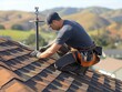 A man is working on a roof, fixing a shingle. Concept of hard work and dedication, as the man is focused on his task. The scene also suggests a sense of pride in his work