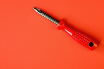 Wall Mural - A red screwdriver laying on an orange surface. Suitable for DIY and construction concepts