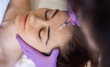 Portrait of young Caucasian woman with closed eyes getting botox cosmetic injection in forehead. Beautiful woman getting botox injection in her face