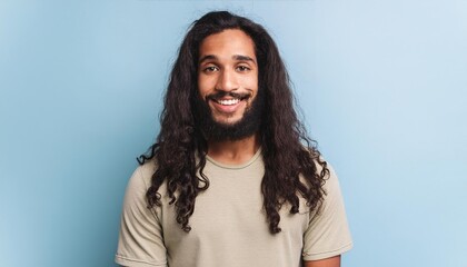 Portrait of a charismatic young man with a bright smile, long wavy hair, and beard posing casually