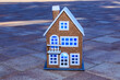 Toy brown house with blue light in the windows on the background of paving slabs