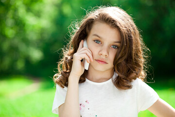 Wall Mural - Portrait of a beautiful young little girl calling by phone