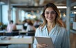 © Jevjenijs - A woman in glasses holds a tablet in a room filled with individuals seated at desks A solitary desk stands in the background