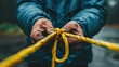   A person tightly grips one rope in each hand in this close-up image