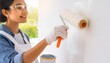 © Marko - young Woman painter hand in white glove painting a room wall with paint roller