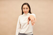 Pretty smiling asian girl in sweater standing against pink studio background, pointing at camera with finger out of focus, choosing you, motivating to move on, go ahead, achieve your goals