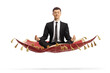 Young man in a black suit sitting on a flying carpet and meditating