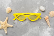 Stylish yellow sunglasses on concrete background, top view. Summer concept