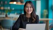 © Bijac - smiling asian businesswoman working on laptop turquoise office background