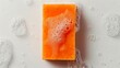 An orange bar of soap with bubbles and foam on a white background. Isolated orange bar of soap with soap bubbles that suggests a feeling of cleanliness.
