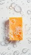 An orange bar of soap with bubbles and foam on a white background. Isolated orange bar of soap with soap bubbles that suggests a feeling of cleanliness.